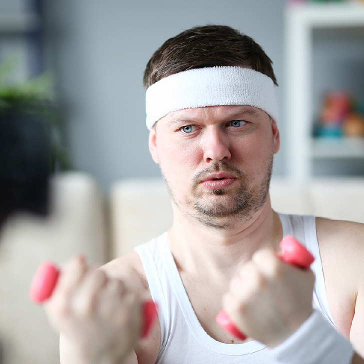 Harry Smith wearing a headband and lifting commically small pink weights